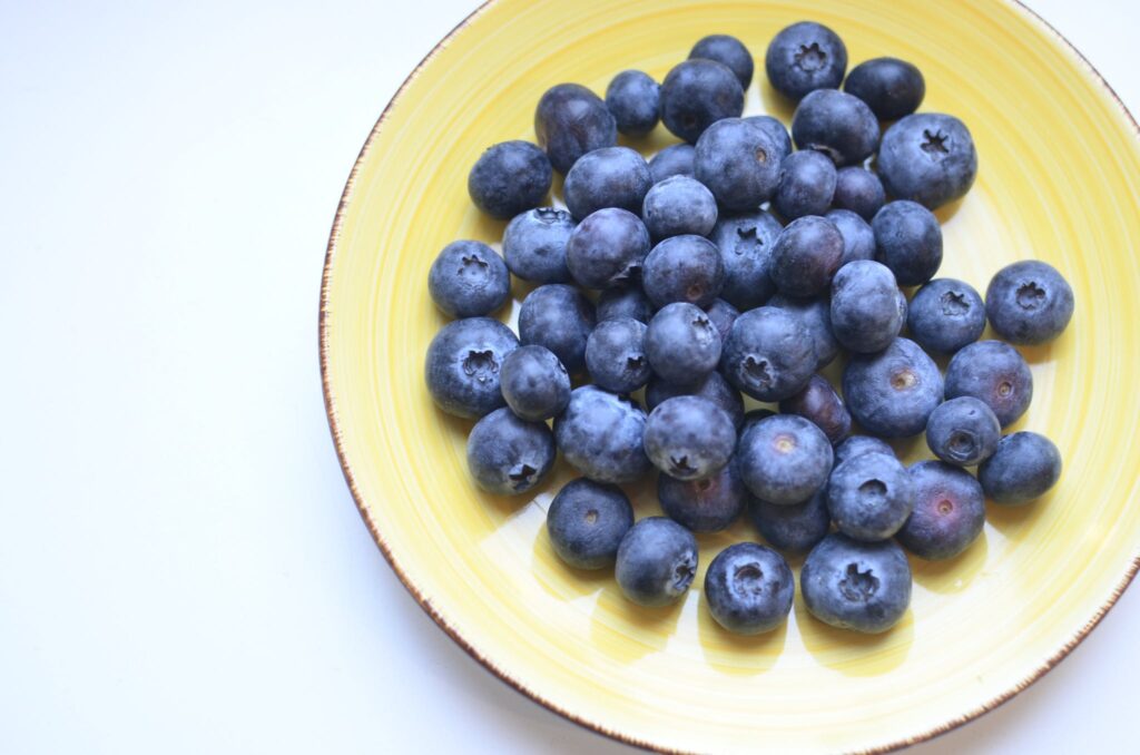 From above of ceramic plate with fresh appetizing berries on table in kitchen